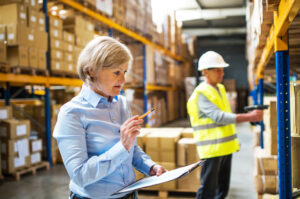 Senior woman manager and man worker working in a warehouse.