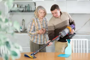 Male salesman tells an elderly woman how to use new cordless vacuum cleaner